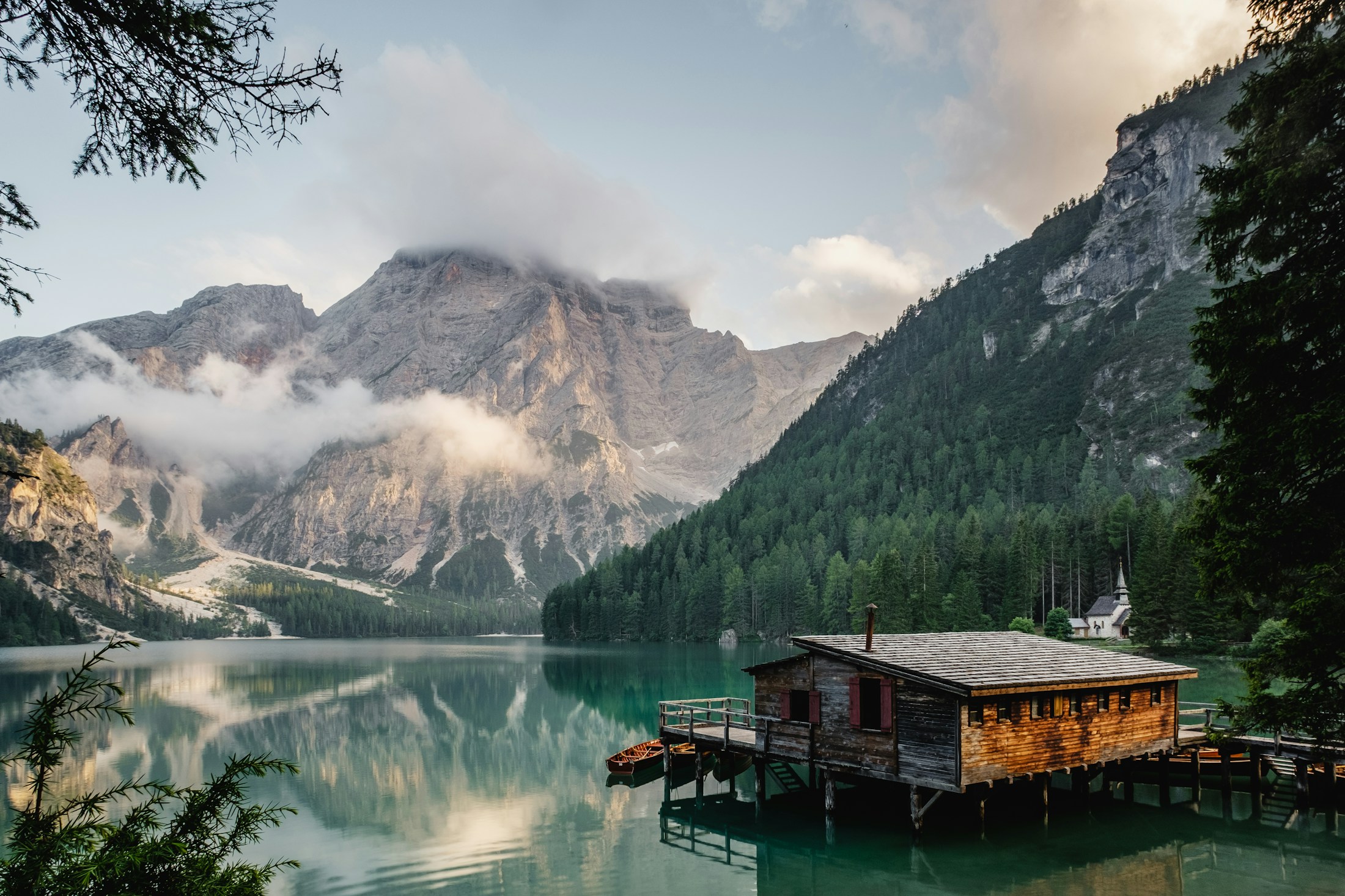 Soft morning light over a still lake, forest and mountain horizon